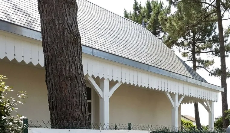 Toit en ardoise et lambrequins blancs d'une villa balnéaire sous les pins maritimes à La Baule-Escoublac